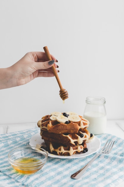 Free photo crop hand pouring honey on waffles