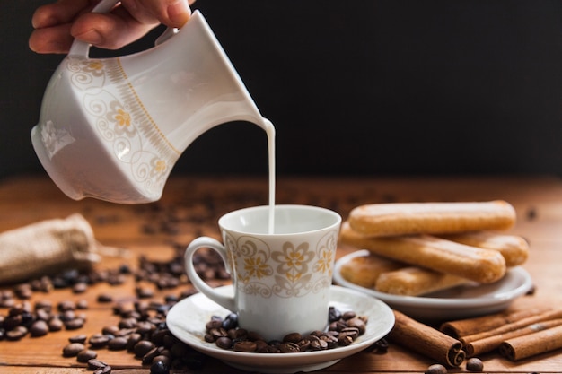 Free photo crop hand pouring milk into cup