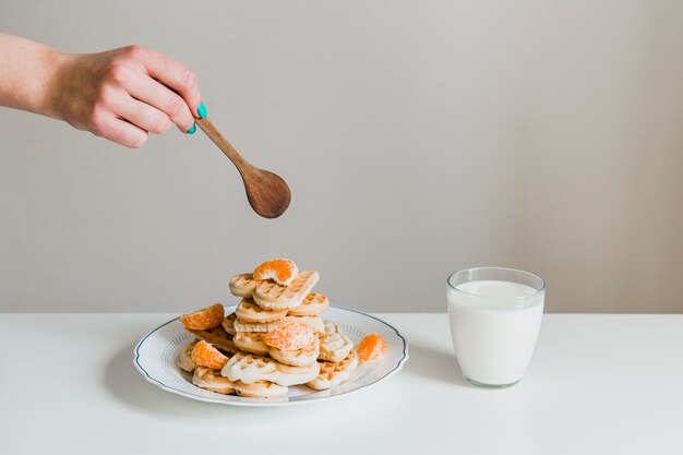 Crop hand pouring sauce on waffles