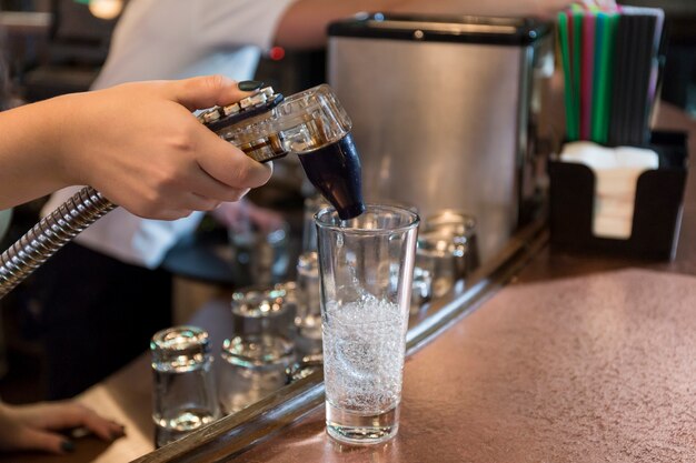 Crop hand pouring soda into glass