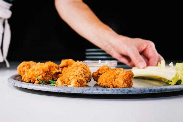 Free photo crop hand putting celery near fried chicken