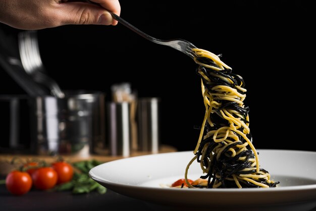 Crop hand taking pasta from plate