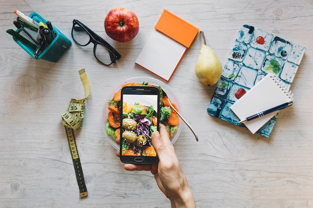 Free photo crop hand taking picture of salad in office