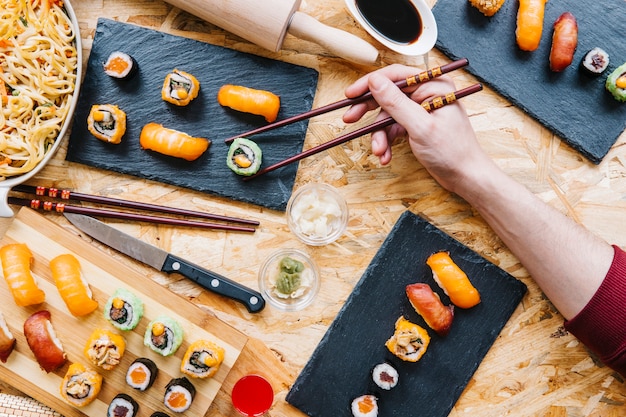 Crop hand taking sushi from board