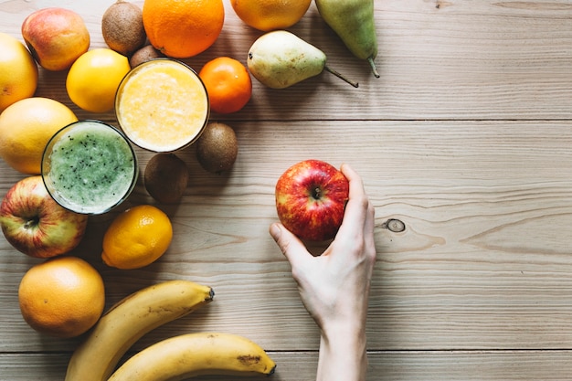 Free Photo crop hand with apple near fruits and smoothie