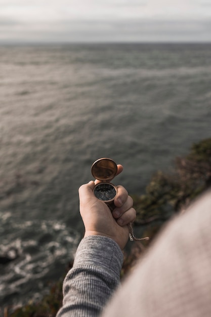 Crop hand with compass near water