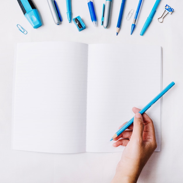 Crop hand with pencil over notebook