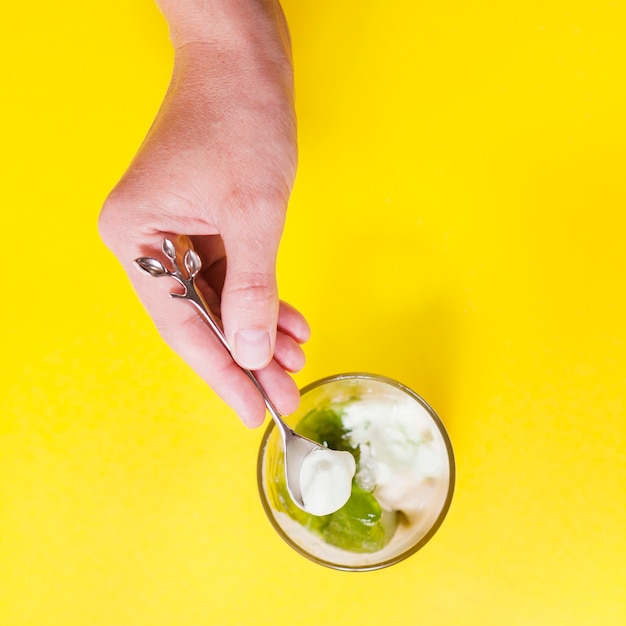 Free Photo crop hand with spoon taking ice-cream