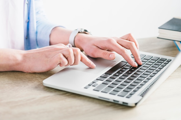 Crop hands browsing laptop on table