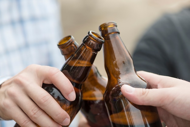 Free photo crop hands clinking beer bottles