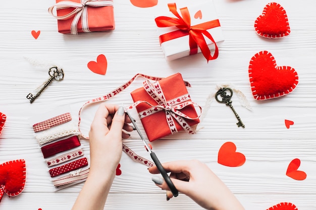 Crop hands cutting ribbon on gift box