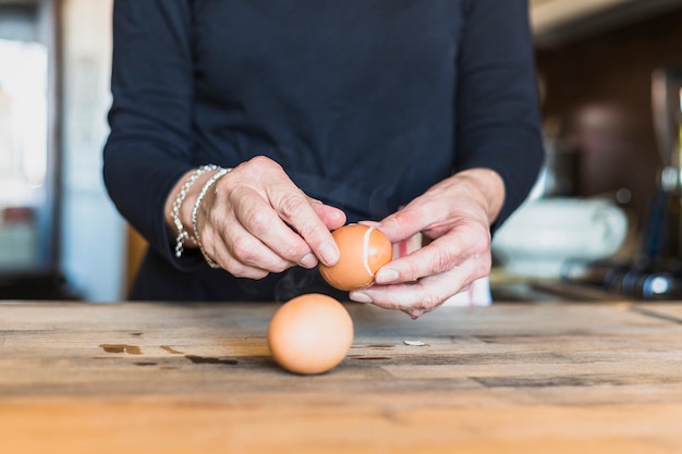 Crop hands of elderly woman cooking in kitchen