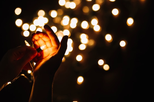 Free photo crop hands holding bulb of garland