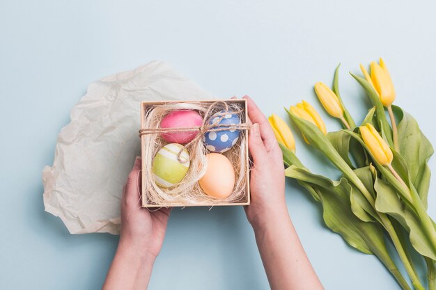 Crop hands holding eggs near tulips