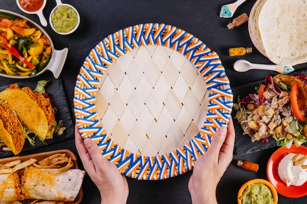 Free photo crop hands holding plate near mexican food