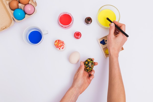 Free Photo crop hands painting flowers on egg