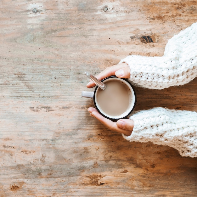 Free Photo crop hands in sweater warming near hot coffee