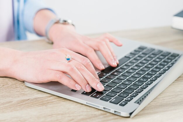 Crop hands typing on laptop in office