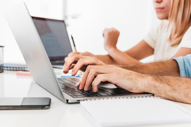 Crop hands typing on laptop at workplace