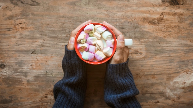 Crop hands warming near hot chocolate