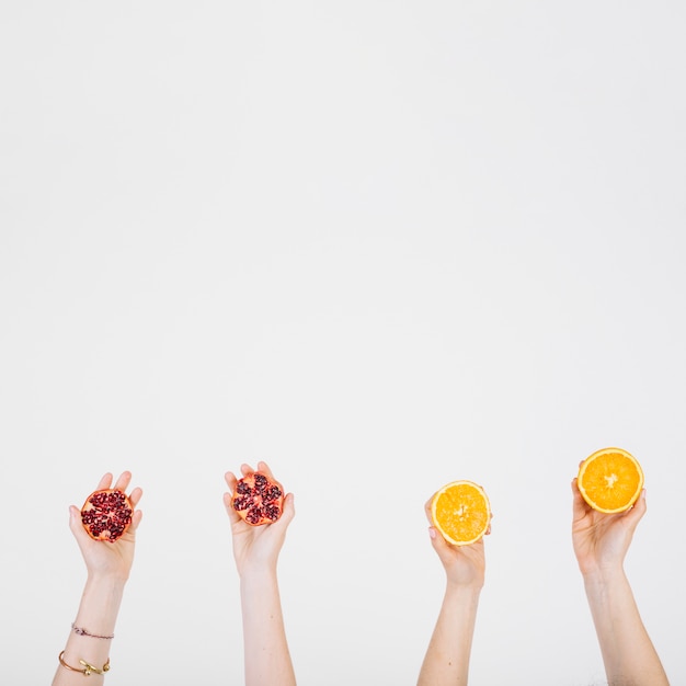 Crop hands with pomegranate and orange