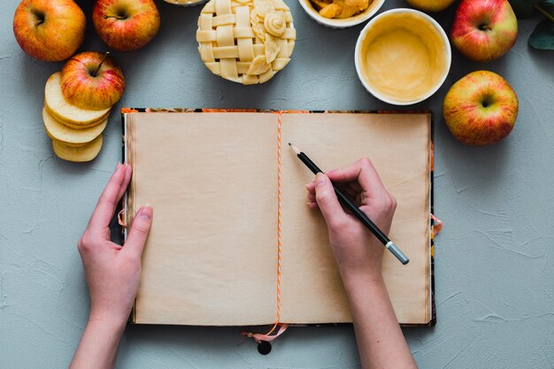 Free photo crop hands writing near apples and pie