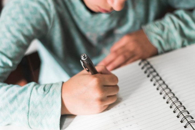 Crop kid writing in notebook