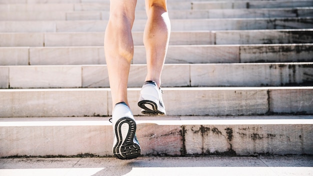 Crop legs in sneakers running upstairs