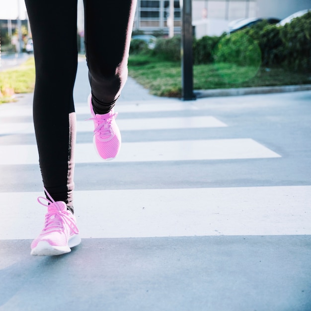 Crop legs sprinting on crosswalk