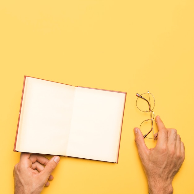 Crop male holding glasses and open notebook