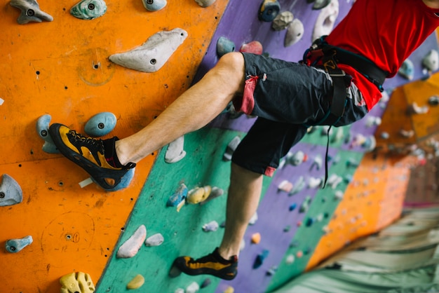 Crop man climbing wall