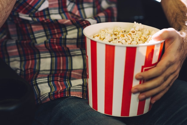 Crop man eating popcorn in cinema