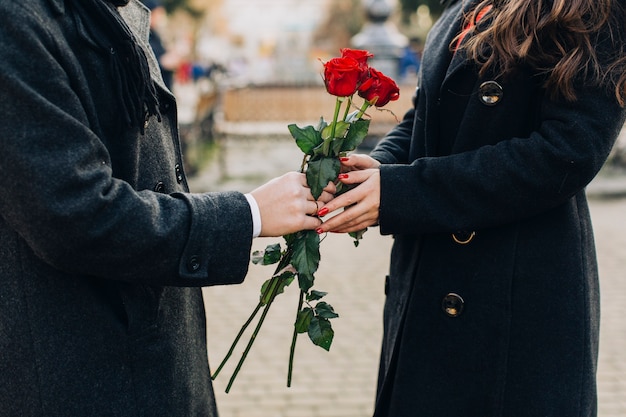 Crop man giving flowers to girlfriend