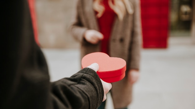 Crop man giving present to woman