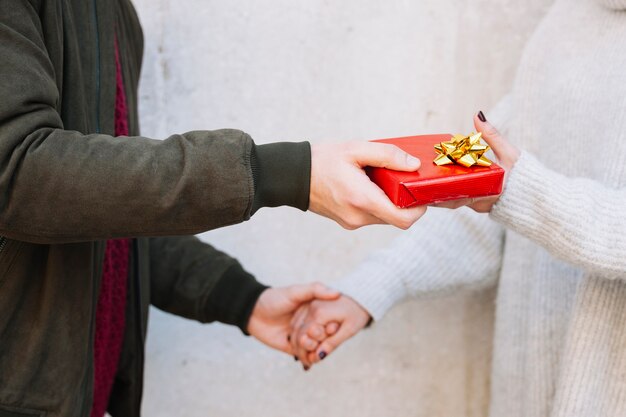 Crop man giving present to woman