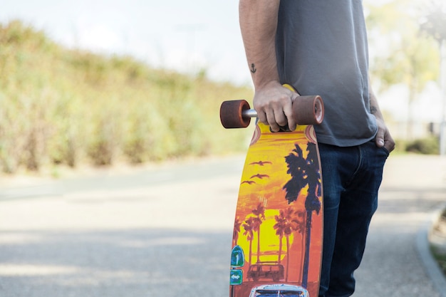 Free photo crop man leaning on longboard