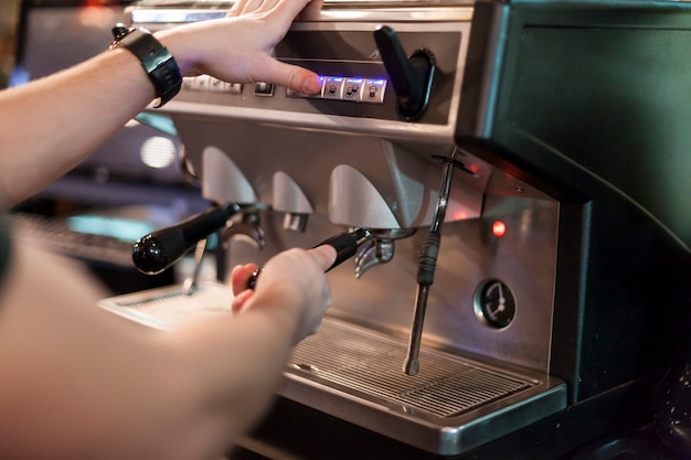 Crop man using coffee machine in cafe