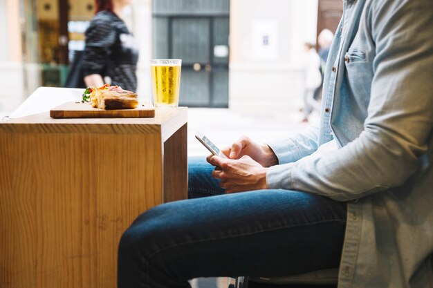 Crop man using smartphone in restaurant