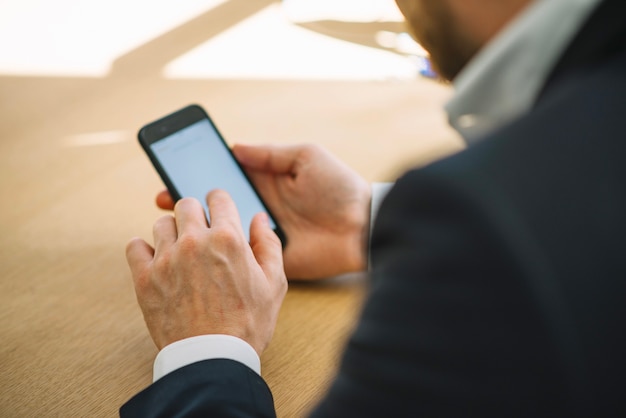 Crop man with smartphone in office