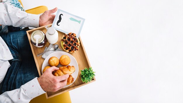 Crop man with tray having breakfast