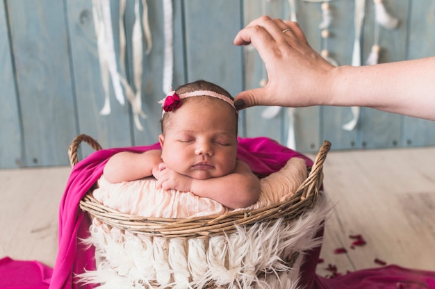 Crop mother touching newborn in basket