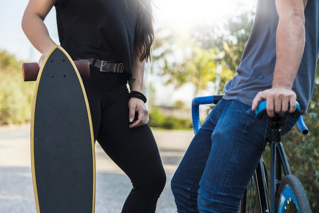 Crop people with bicycle and longboard