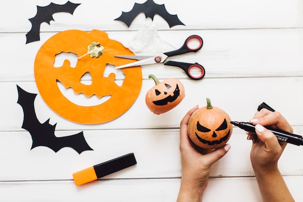 Free photo crop person drawing grin on pumpkin