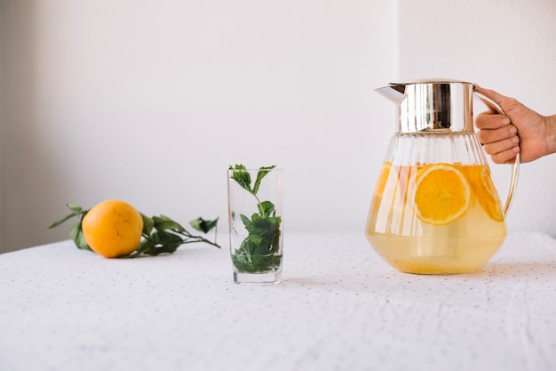 Free photo crop person serving orange lemonade