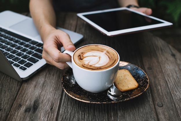 Crop person with tablet drinking coffee