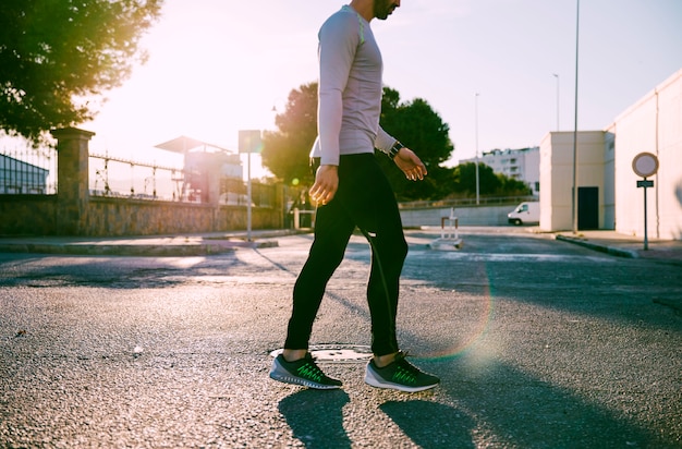 Crop sportsman walking on street