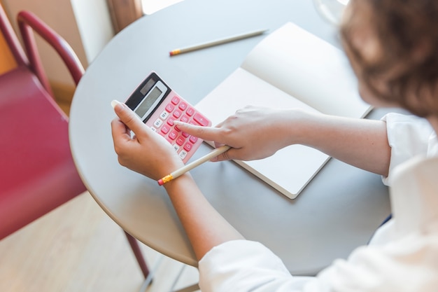 Free photo crop teen using calculator at table