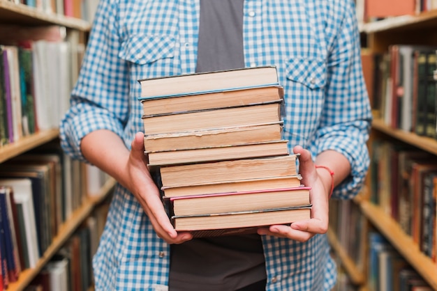 Free photo crop teenager with books between bookshelves