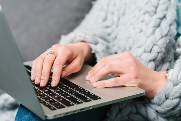 Free photo crop woman in blanket using laptop