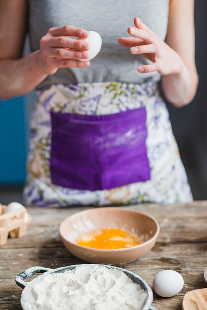 Crop woman breaking eggs